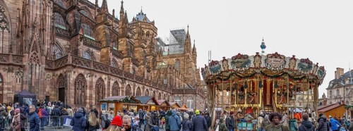 Panoramic photo of the carousel at the Christmas market at the High Gothic Strasbourg Cathedral,