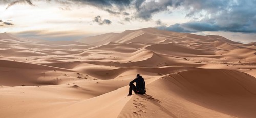 A person sitting in the Erg Chebbi desert in the African Sahara, Morocco, Africa