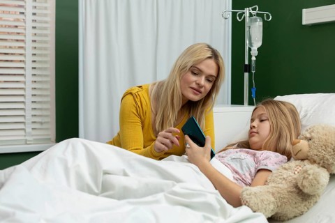 In a heartfelt hospital moment, a woman and a girl share a phone, reinforcing their connection in a