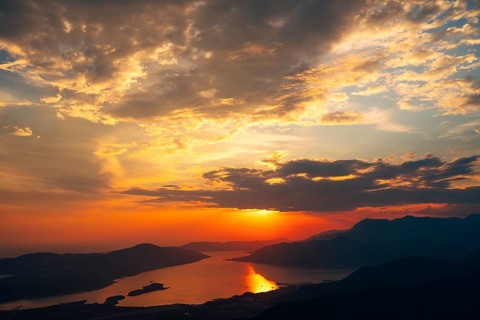 Orange clouds in the rays of the setting sun over the bay. View from Mount Lovcen.