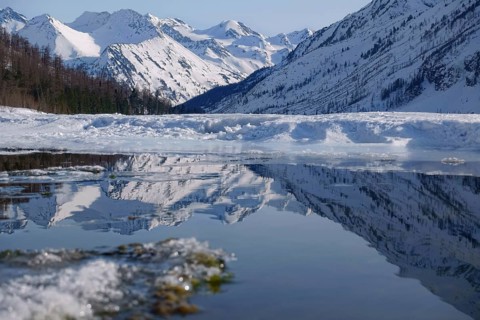 Winter landscape with mountain lake and high mountains reflected
