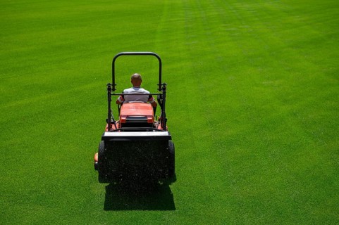 Mowing grass at the football stadium in Lubin, Poland, Europe