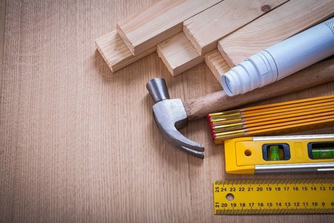 Wooden studs and meter ruler hammer blueprints construction level on wood background building and