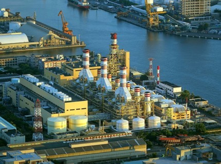 A large factory and industrial complex situated on the waterfront by the harbor