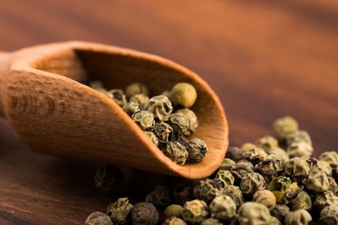Green peppercorns on a wooden background