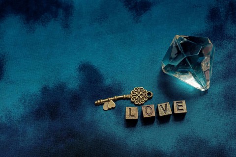 Ornamental key and fake diamond beside love wording with metal letters