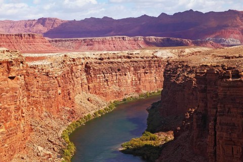 Magnificent Colorado River slowly flows into the high banks of red sandstone