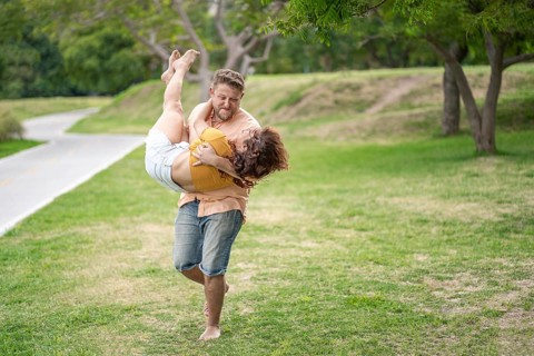 Man running in a park carrying his girlfriend in his arms