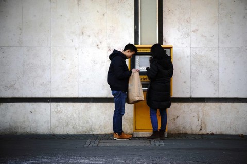Frankfurt, Germany - January 05, 2017: Two young Asian tourists stand at a stamp vending machine at