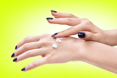 Beautiful female hands with cream on the green background