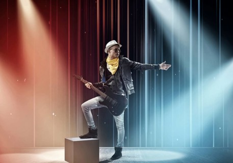 Young man rock musician in lights of stage