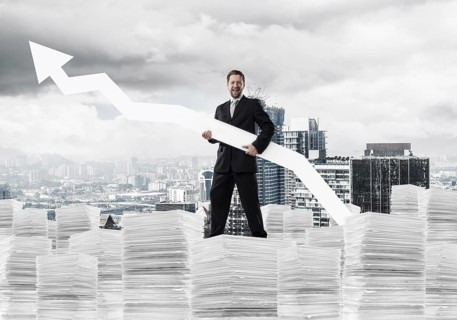 Young and ambitious businessman in suit holding big white arrow in hand and pointing away while