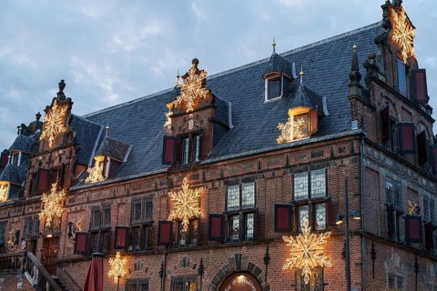 Old building with Christmas decorations and stars on the roof under a cloudy sky, nijmegen, the