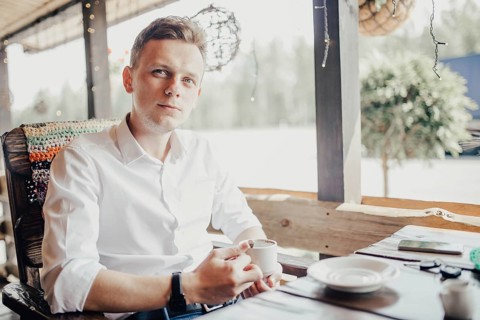 Man enjoying a cup of coffee on a patio, ambient light surrounding him
