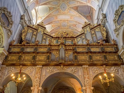 Lavishly decorated organ in a baroque church with detailed ceiling decorations and majestic