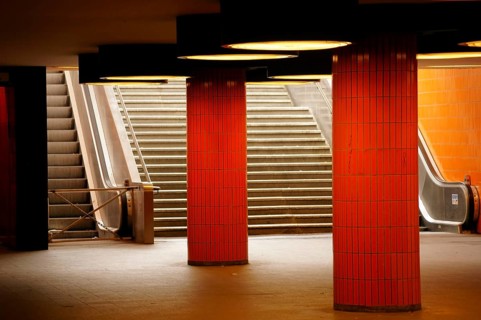 The steps and a disused escalator of a tunnel exit with orange tiles and columns