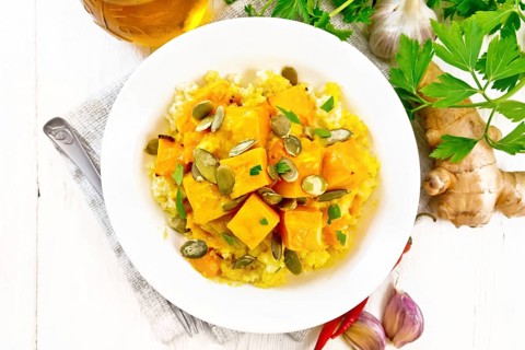 Millet porridge with spicy pumpkin sauce and seeds in a plate on a towel, hot pepper, ginger root,