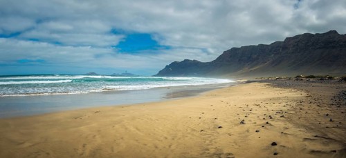 Panorama view on Famara beach on the Canary Island of Lanzarote, with some windsurfing in the far