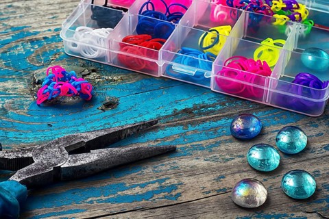Beads, pliers, and other needlework accessories on outdated turquoise wooden background