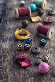 The spool of thread, beads and wire for needlework on wooden background