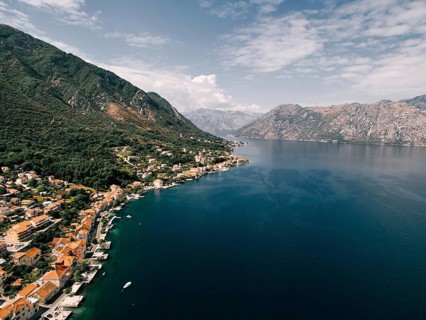 Red roofs of houses with private piers on the shores of the Bay of Kotor. Dobrota, Montenegro.