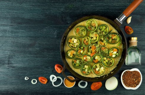 Zucchini in the background. Fried young sliced courgettes in a pan on a dark background. The view
