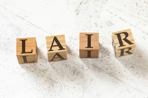 Four wooden cubes with letters LAIR (meaning Listen Acknowledge Identify Reverse) on white working