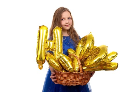 Little girl in a festive blue dress holds a golden set of happy birthday inflatable letters.