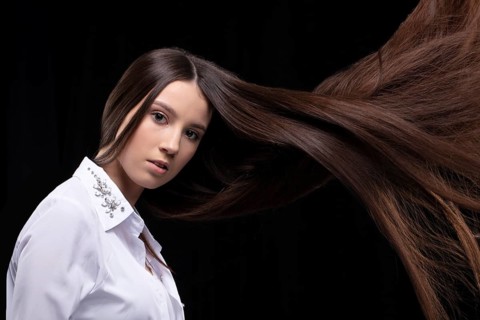 Beautiful brunette with long flying hair on a dark background