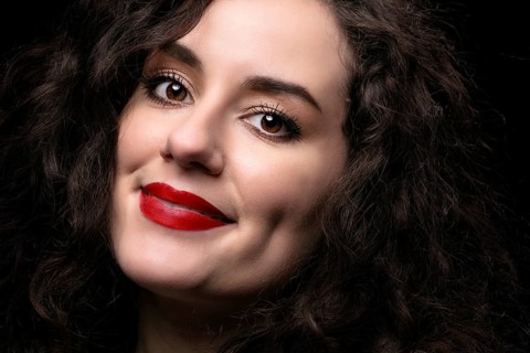 Portrait of a beautiful brunette girl with curly hair and red lipstick