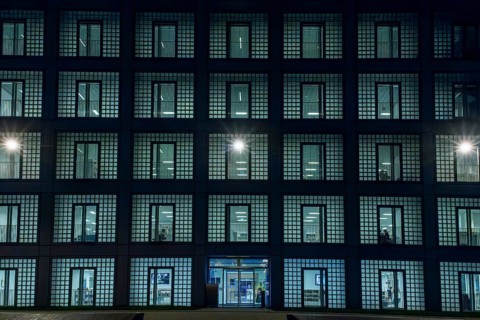 Night shot of the façade with entrance door and countless windows of the cube-shaped city library