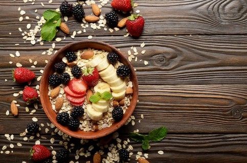 Flat lay top view at Fruit healthy muesli with banana strawberry almonds and blackberry in clay