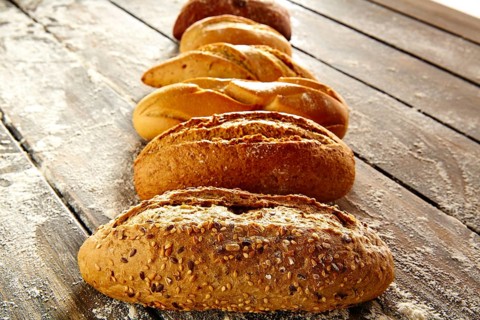 Breads varied in a row on rustic wood table with wheat flour