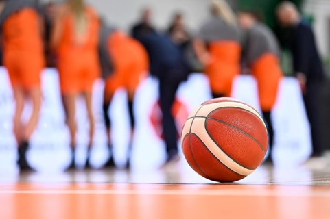 The ball lying on the parquet and the basketball team in the background.