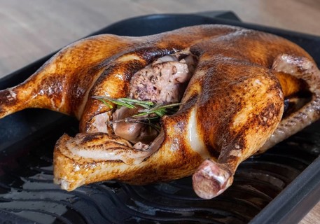 Close-up of a whole roasted or slow-baked duck in a frying pan