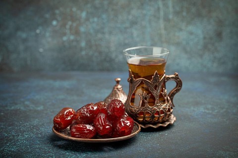 Breaking fasting with dried dates during Ramadan Kareem, Iftar meal with dates and Arab tea in