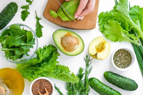 Woman cooking salad of fresh green vegetables and herbs. Cooking healthy diet or vegetarian food.