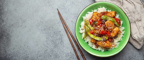 Asian sweet and sour sticky chicken with vegetables stir-fry and rice in ceramic bowl with