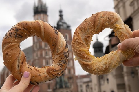Tourist woman eating bagel obwarzanek traditional polish cuisine snack waling on Market square St.
