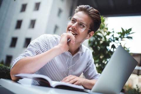 Happy handsome businessman mixes his break and job outdoors, businessman with headphones write some