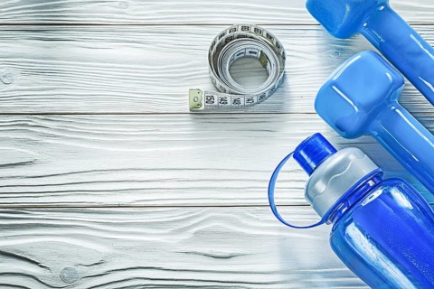 Dumbbells measuring tape water bottle on wooden board fitness concept