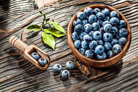 Raw huckleberries in wooden spoon bowl