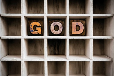 The word GOD written in vintage ink stained wooden letterpress type in a partitioned printer's