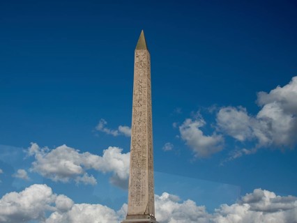 Massive obelisk in front of a clear blue sky with white clouds, Paris, France, Europe