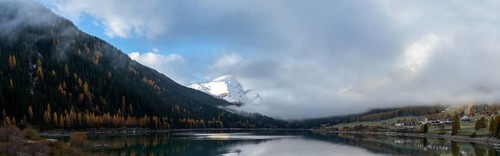 A panorama view of Lake Sufers and Pizzo Tambo and fall foliage forest reflections in the lake
