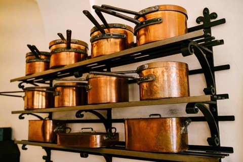 Pots, ladles, tray and saucepan made of copper, in various sizes, on massive metal shelves, fixed