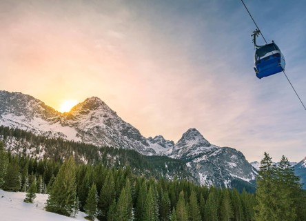 Winter landscape with evergreen fir forests, the Austrian Alps mountains and a cable car, in