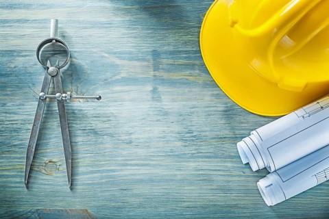 Pair of compasses blueprints hard hat on wooden board construction concept