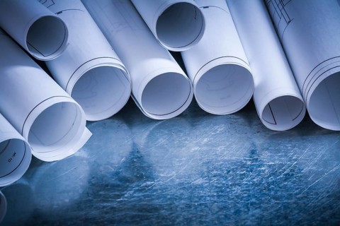 Set of rolled up white construction drawings on scratched silver-metal surface building and