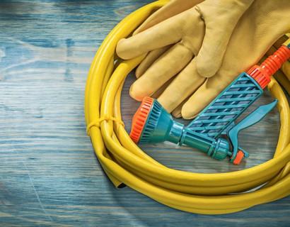 Leather protective gloves garden hose on wooden board gardening concept
